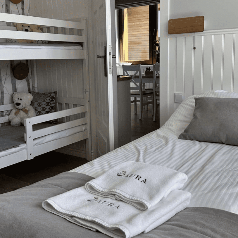 Sypialnia znajdująca się w apartamencie wraz z łóżkiem podwójnym oraz łóżkiem piętrowym przy wejściu do salonu